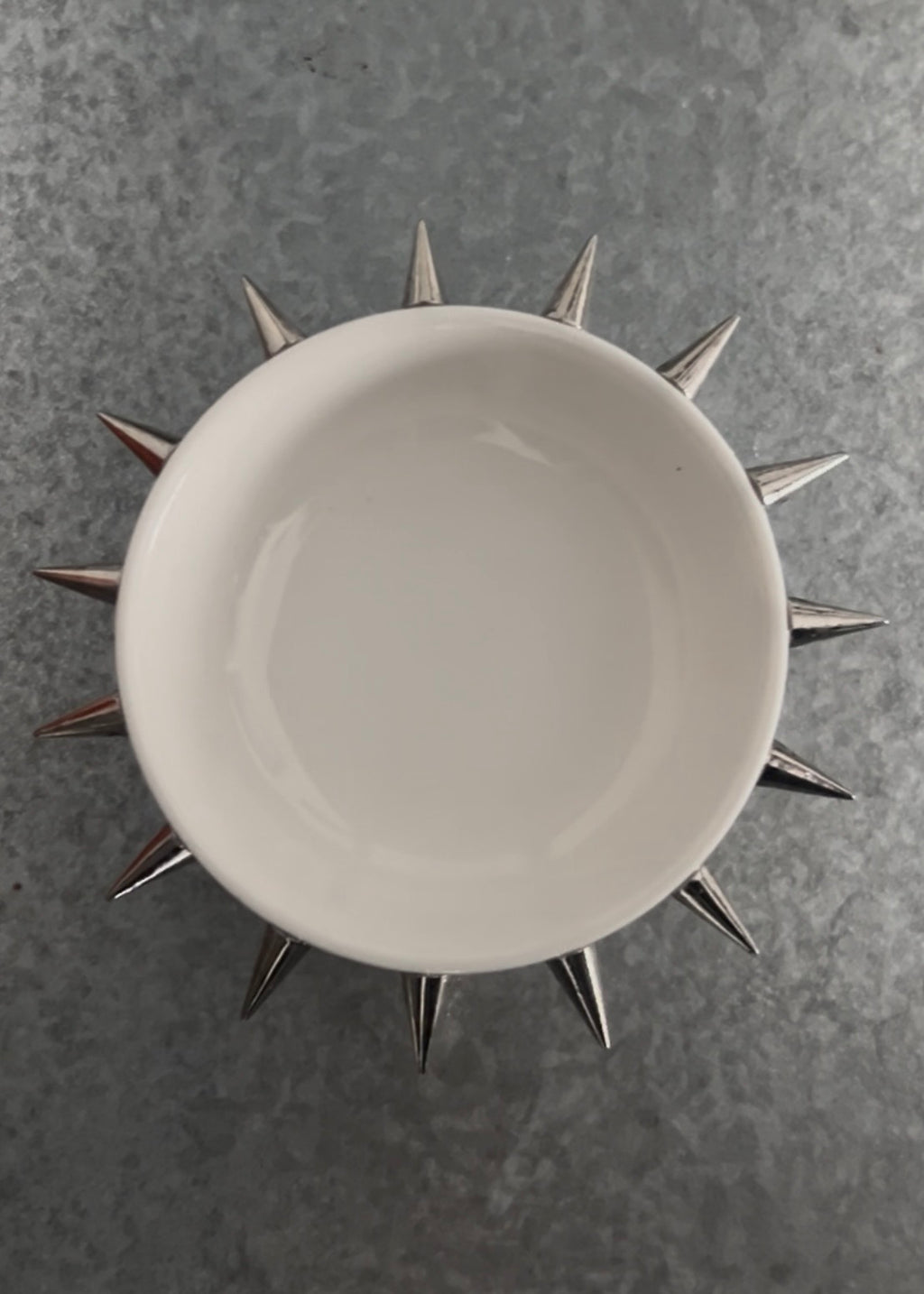 White ceramic plate with metallic spike-like decorations on a gray background