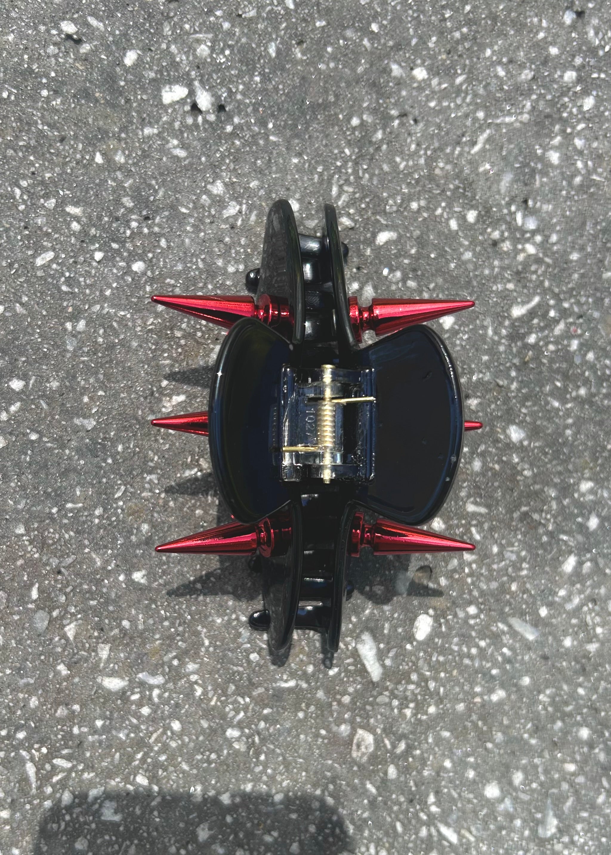 Black and red claw clip on a concrete surface