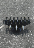 Black and silver spiked claw clip on a concrete surface