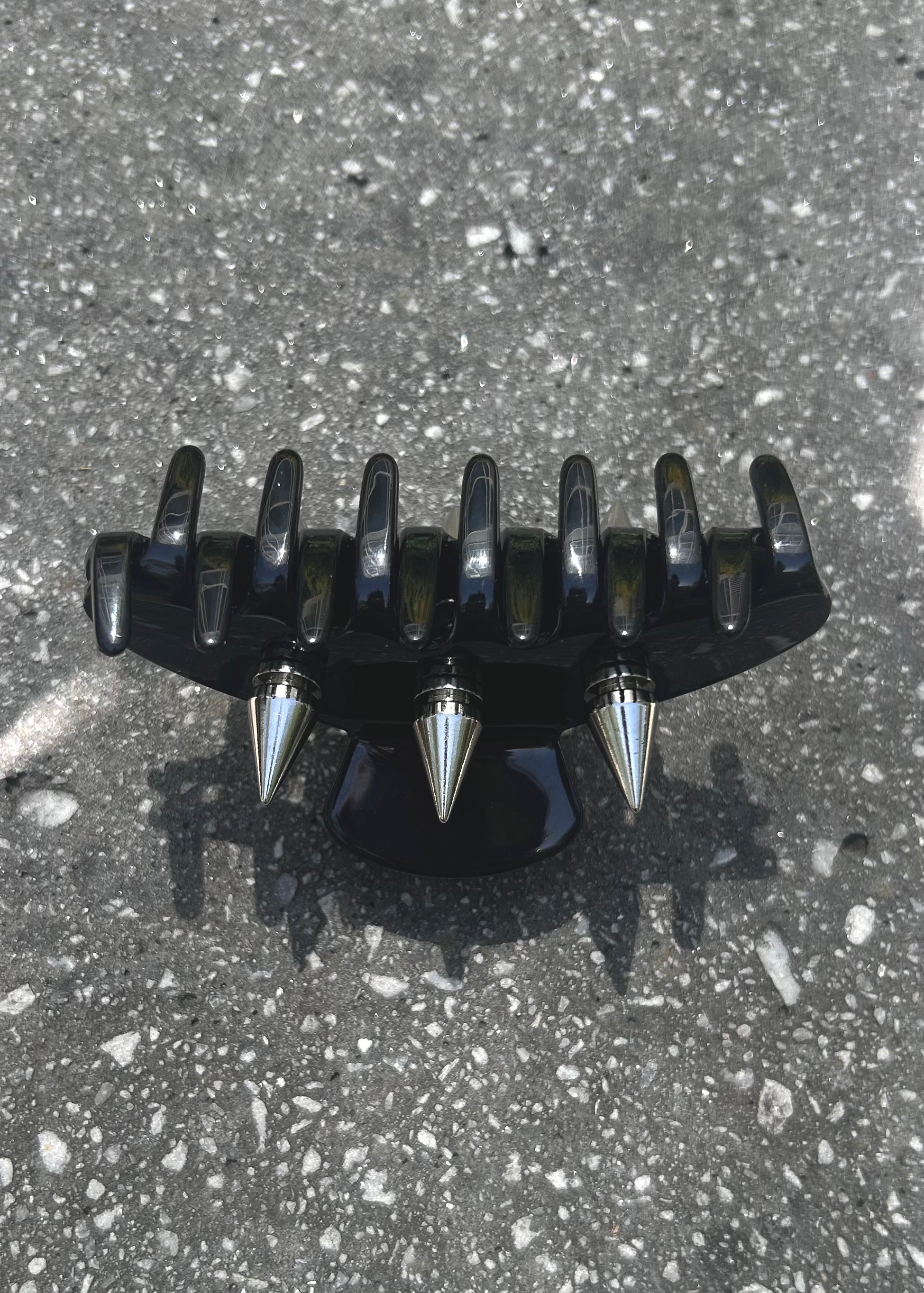 Black and silver spiked claw clip on a concrete surface