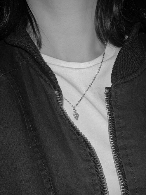 Person wearing a silver necklace with diamond pendant