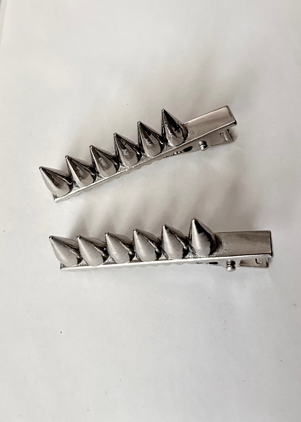 Two metallic spike hair clips on a white background