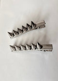 Two metallic spike hair clips on a white background