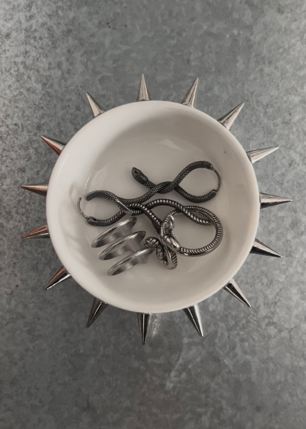 Circular white dish with spikes attached on a grey background with rings 