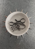 Circular white dish with spikes attached on a grey background with rings 