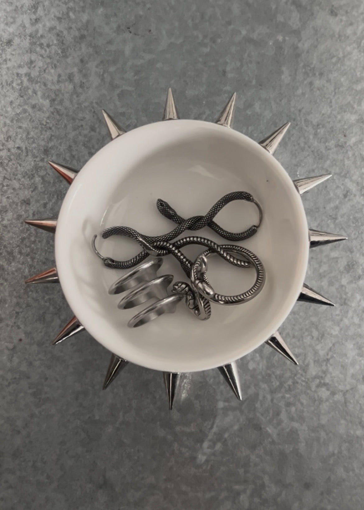 Circular white dish with spikes attached on a grey background with rings 
