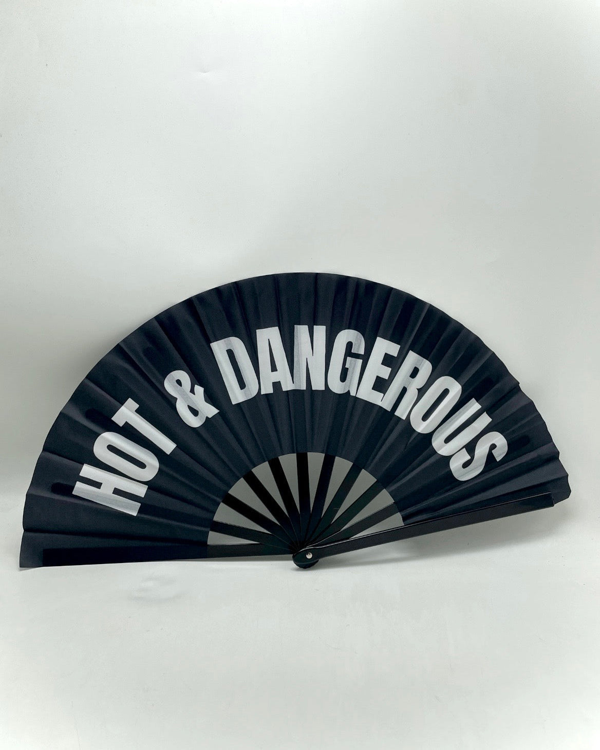 Black hand-fan with printed words “HOT & DANGEROUS”