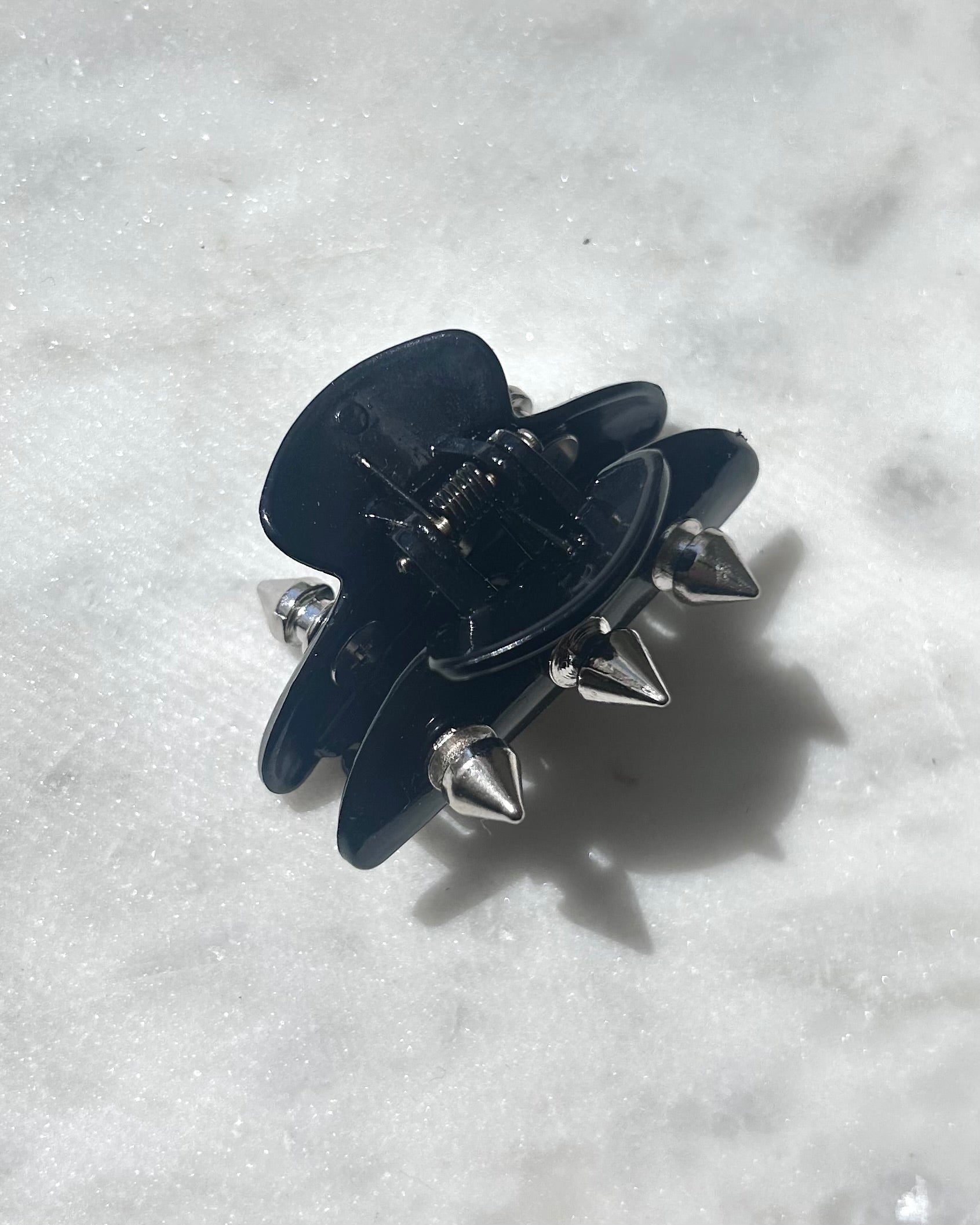 Black hair clip with silver spikes on a white background