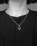 Person wearing silver necklace with a horseshoe charm