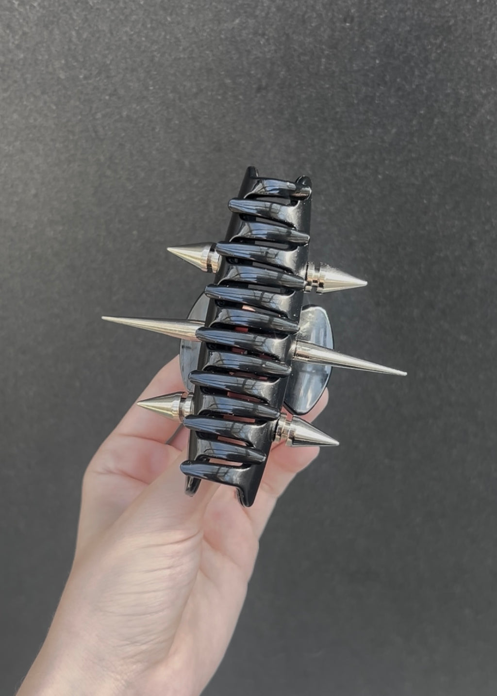Black and silver spiked claw clip on a concrete surface