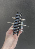 Black and silver spiked claw clip on a concrete surface