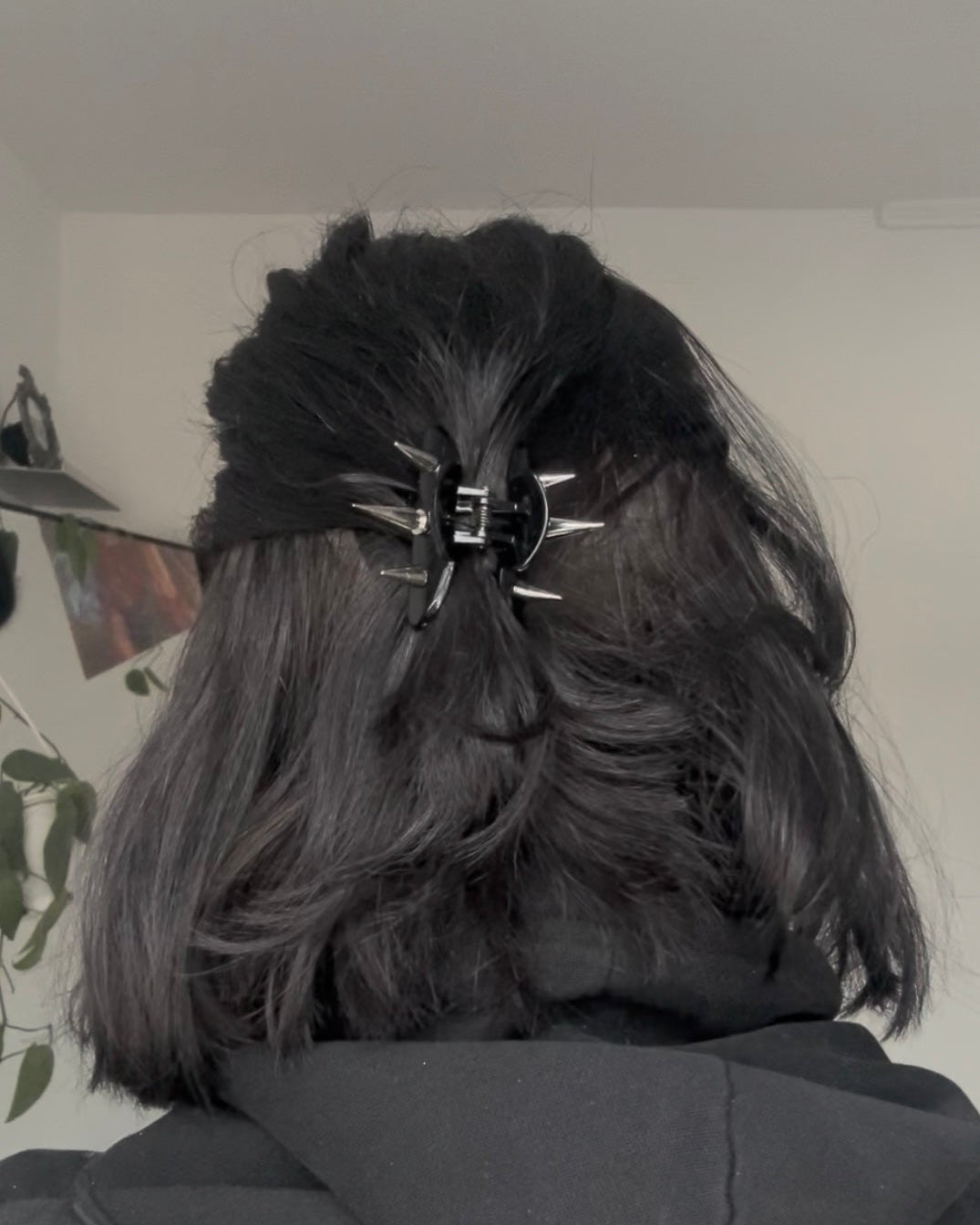 Person with dark hair wearing a black hoodie and a spikey claw clip