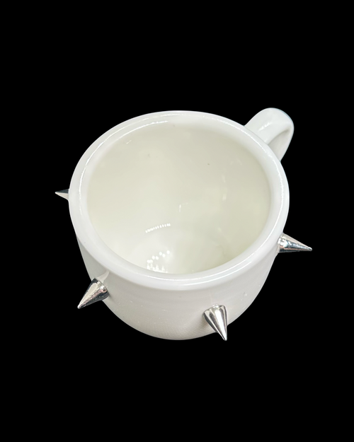 White mug with spike designs on a black background