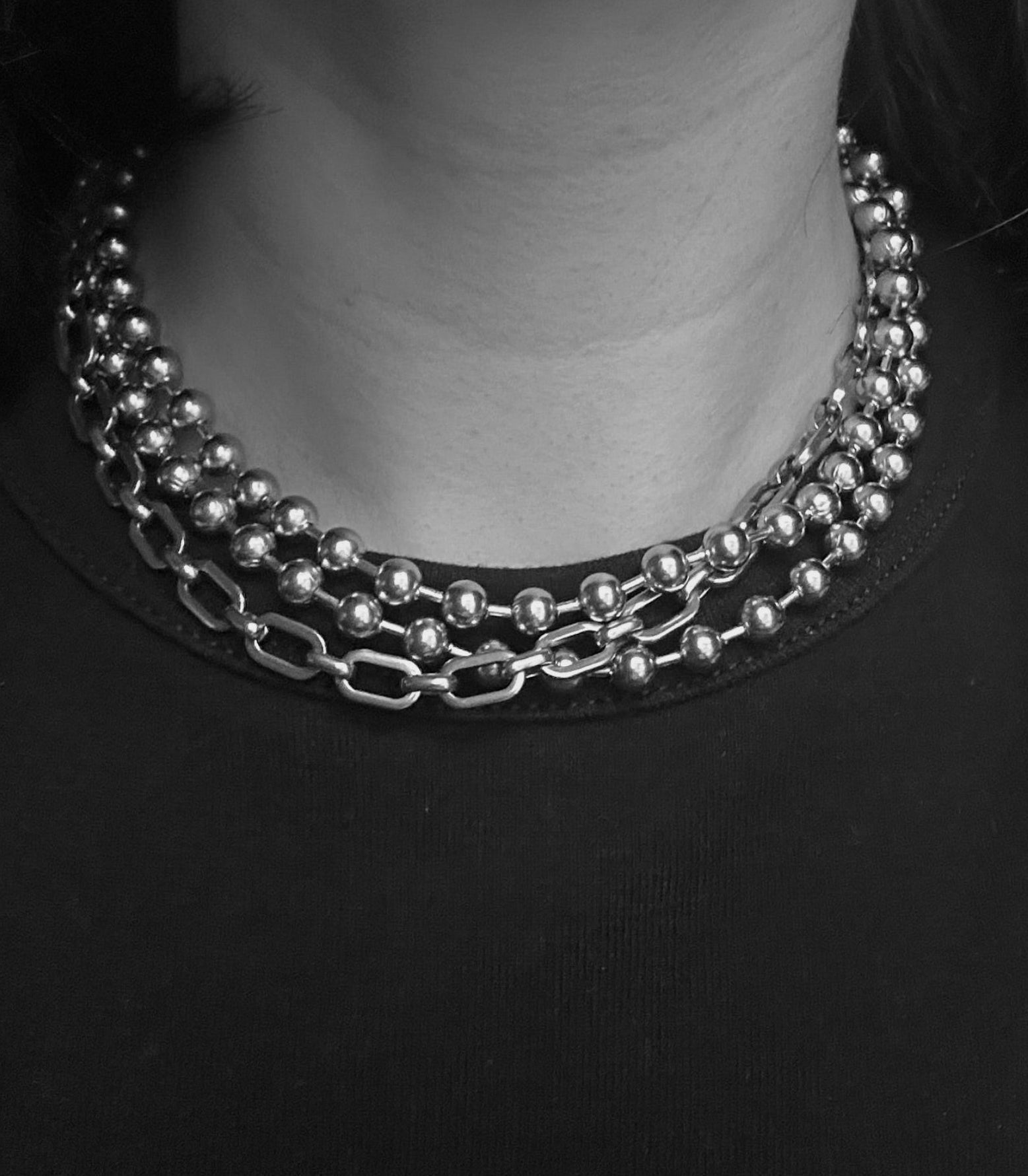 Three-chain silver necklace with beads and chain on a black background