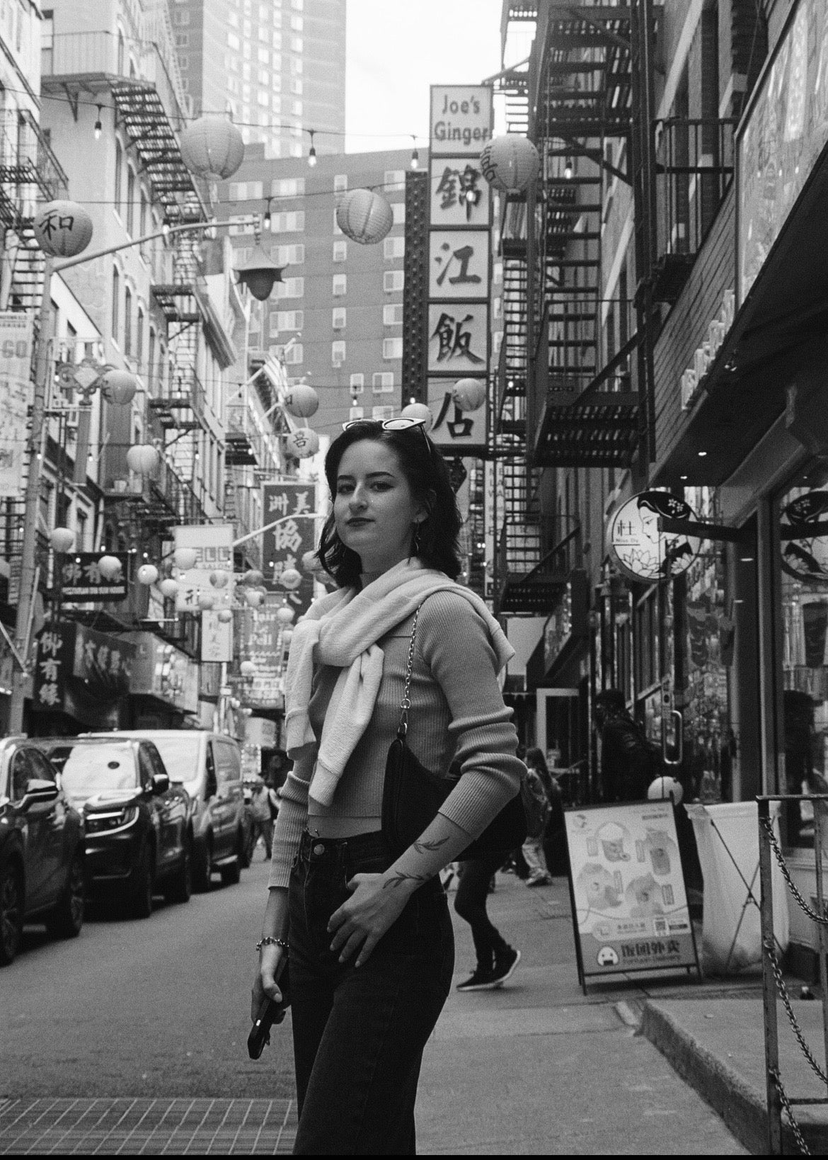 Woman standing on a city street with buildings and signs in the background